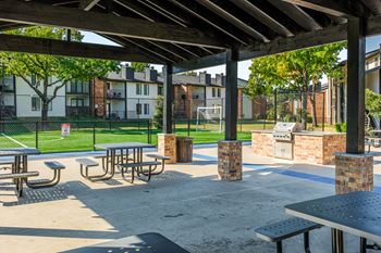 A park with tables and benches under a roof.